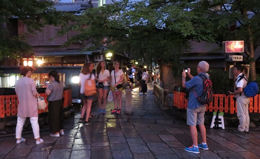 祇園の街並みを背景にカメラを構える観光客